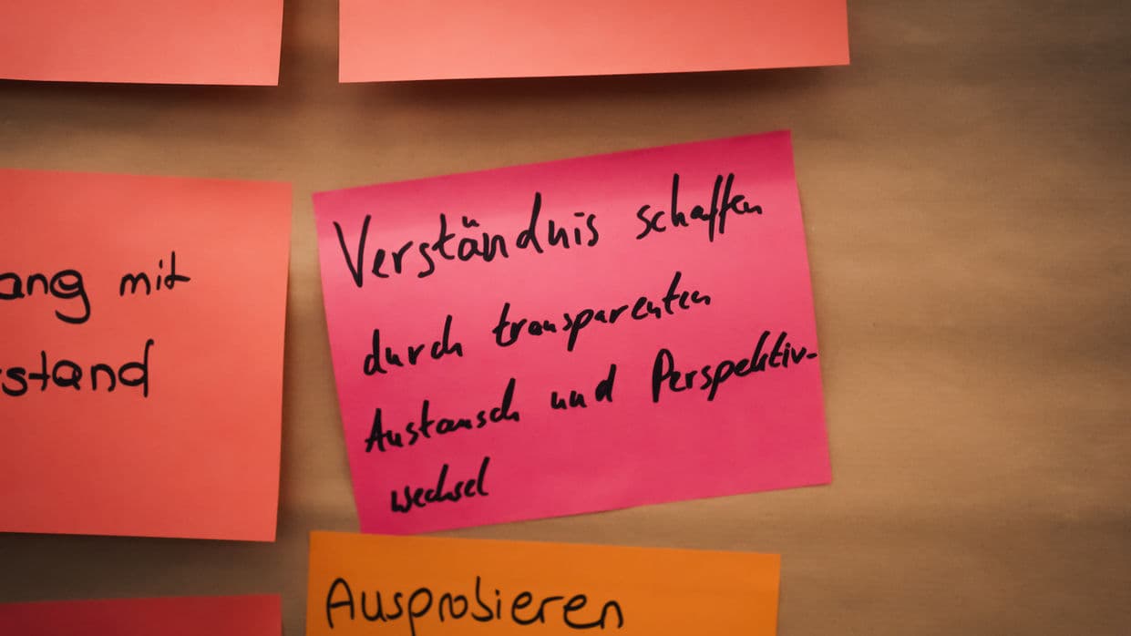 Nahaufnahme beschrifteter Moderationskarten zum Thema Verständnis schaffen durch transparenten Austausch