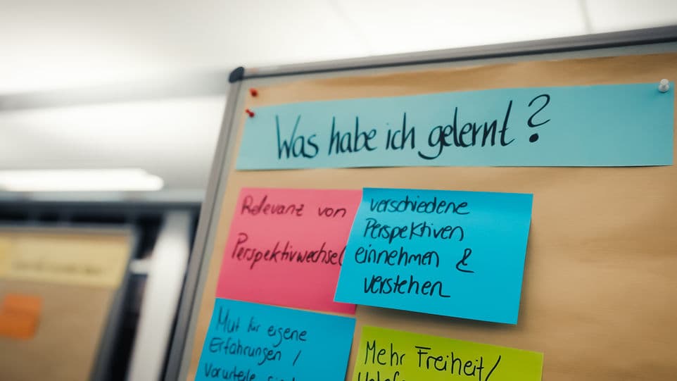 Pinnwand mit der Frage „Was habe ich gelernt?“ und bunten Karten mit Antworten
