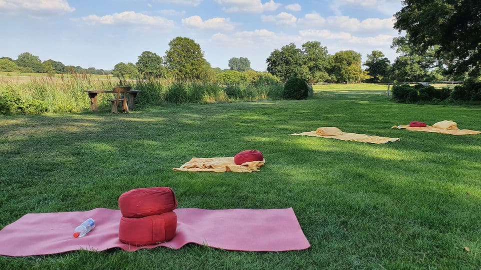 Auf einer Wiese ausgelegte Matten, Kissen und Decken für eine Session im Freien
