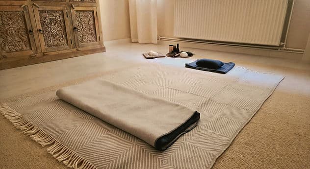 Vorbereiteter Platz für eine Atemreise: Matte, gefaltete Decke und Kissen auf dem Boden