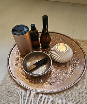 Messingtablett mit Duftölen, Klangschale und einer brennenden Kerze