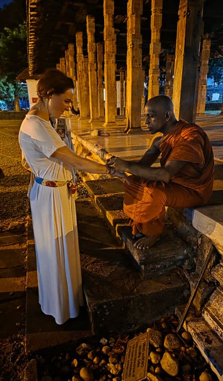 Annika Brüggemann begrüßt bei Abendlicht einen buddhistischen Mönch auf den Stufen einer Tempelanlage